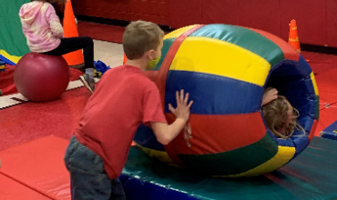 Boy rolls a student inside a ball