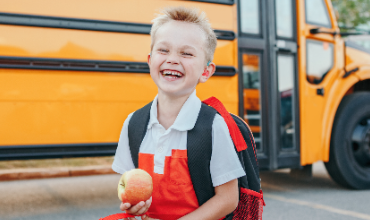 Boy with apple outside in front of bus