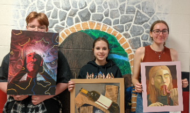 three students with artwork