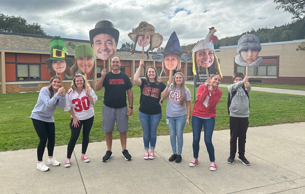 Faculty and staff smiling for a picture with cutouts of their heads after the middle school pep rally 