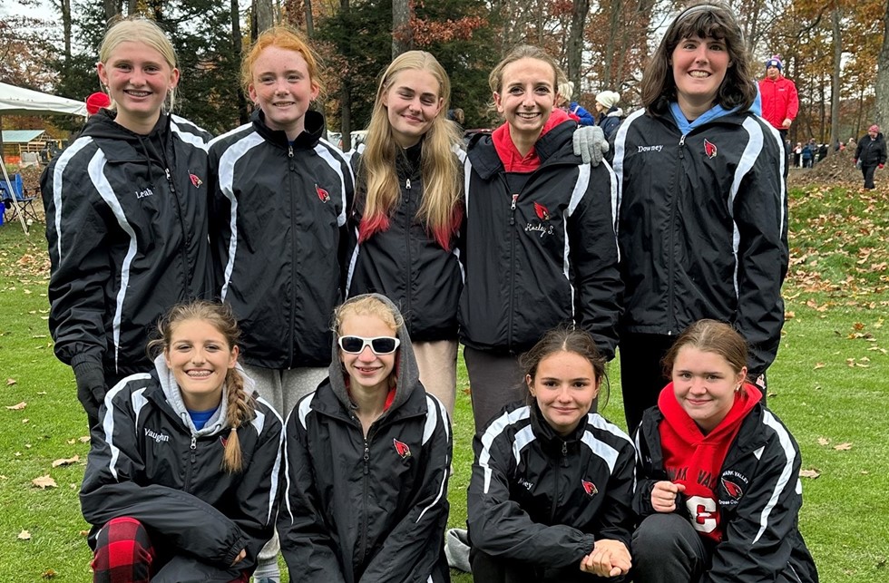 The girls varsity cross country team smiling for a photo 