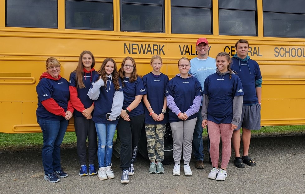 Interact club students smiling for a photo against a school bus