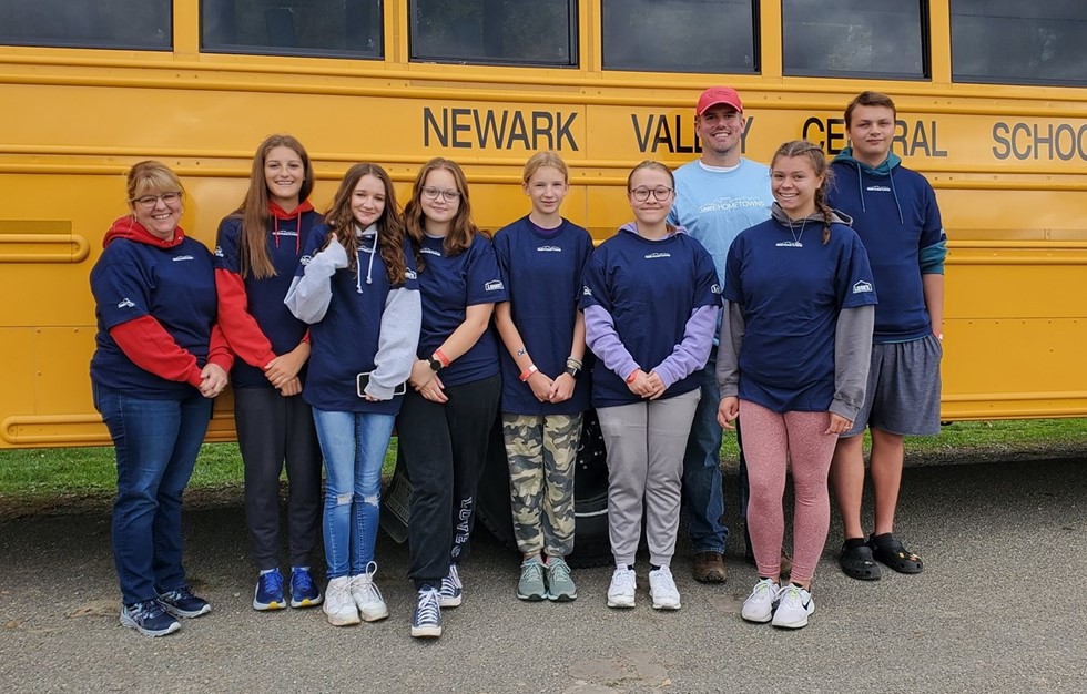 Interact club students smiling for a photo against a school bus