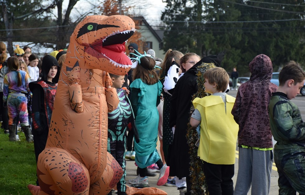 Dinosaur costume with students in the halloween parade