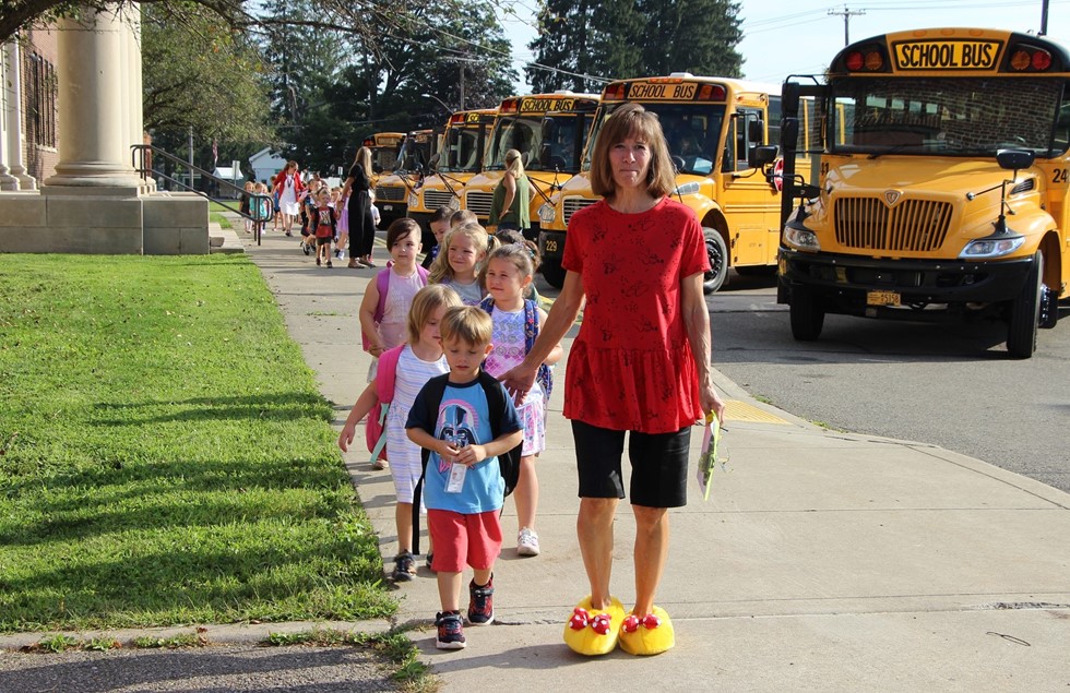 Students walking in to school in front of school buses