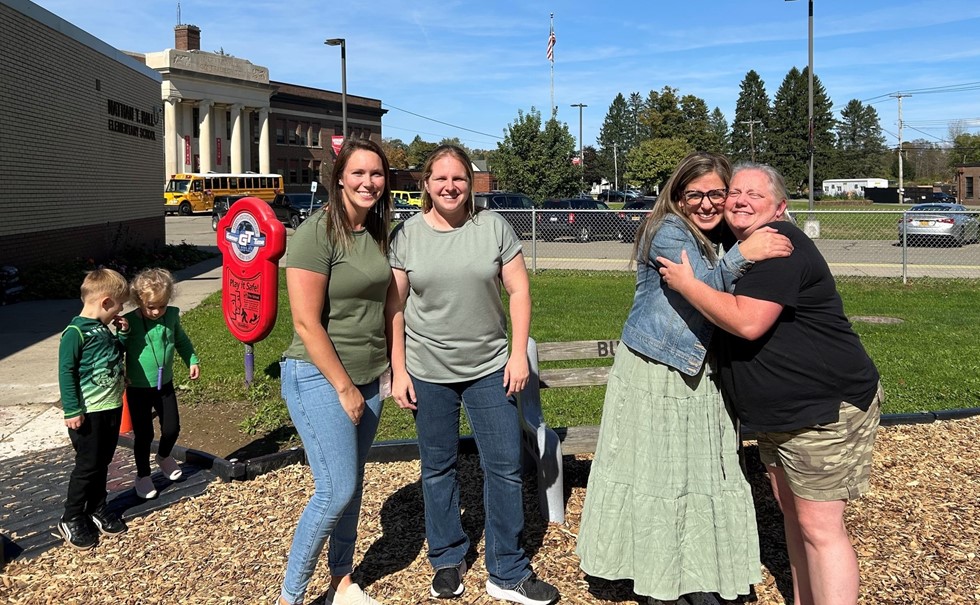 Four adults and two children outside wearing green