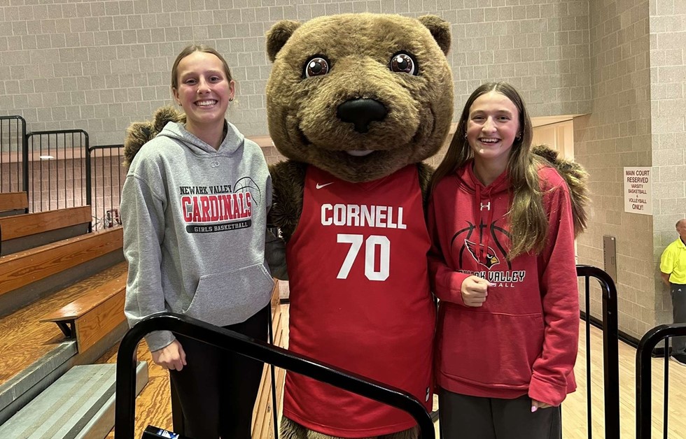 Two students with the Cornell bear mascot in a gym