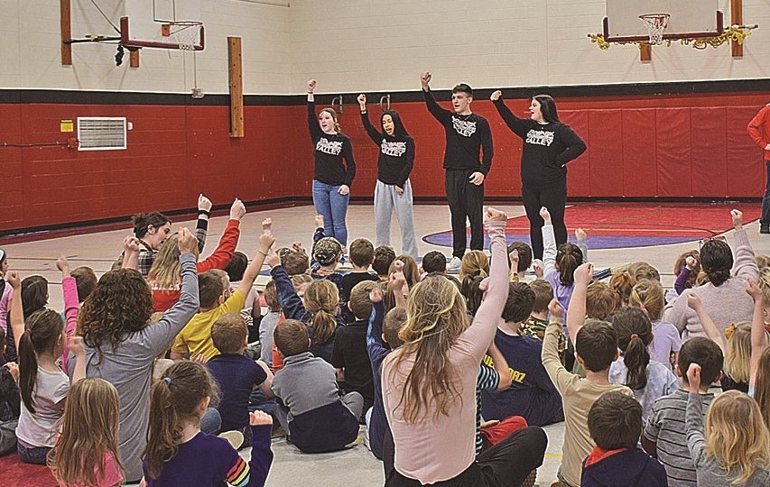 Students learning a cheer from cheerleaders 